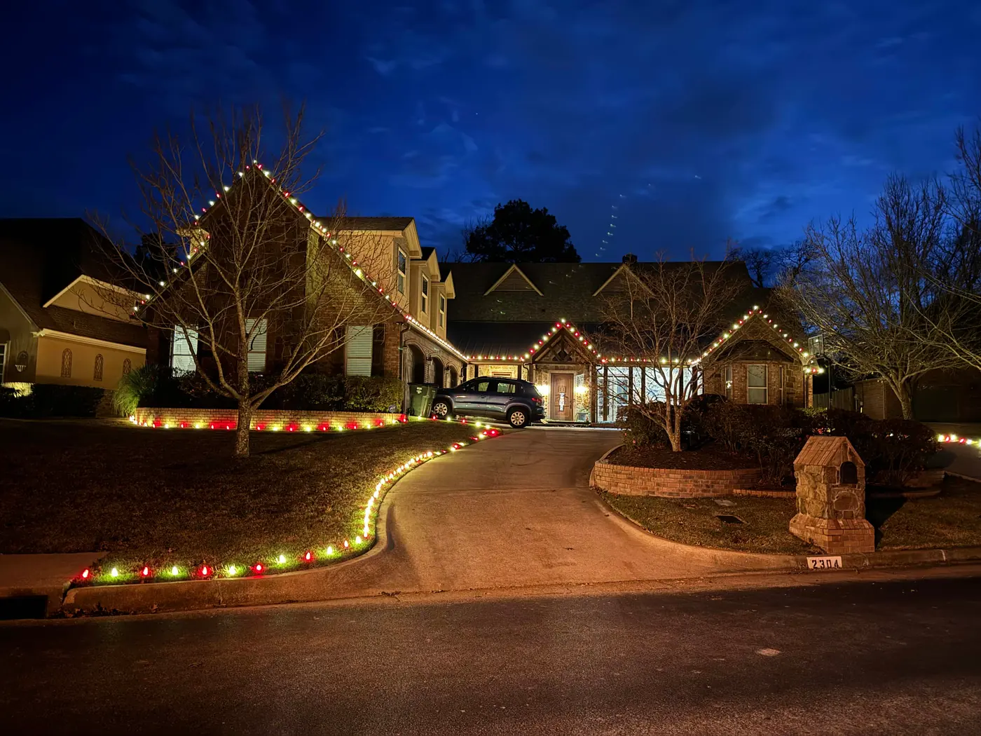 Brick and stone home with colorful holiday roofline lights