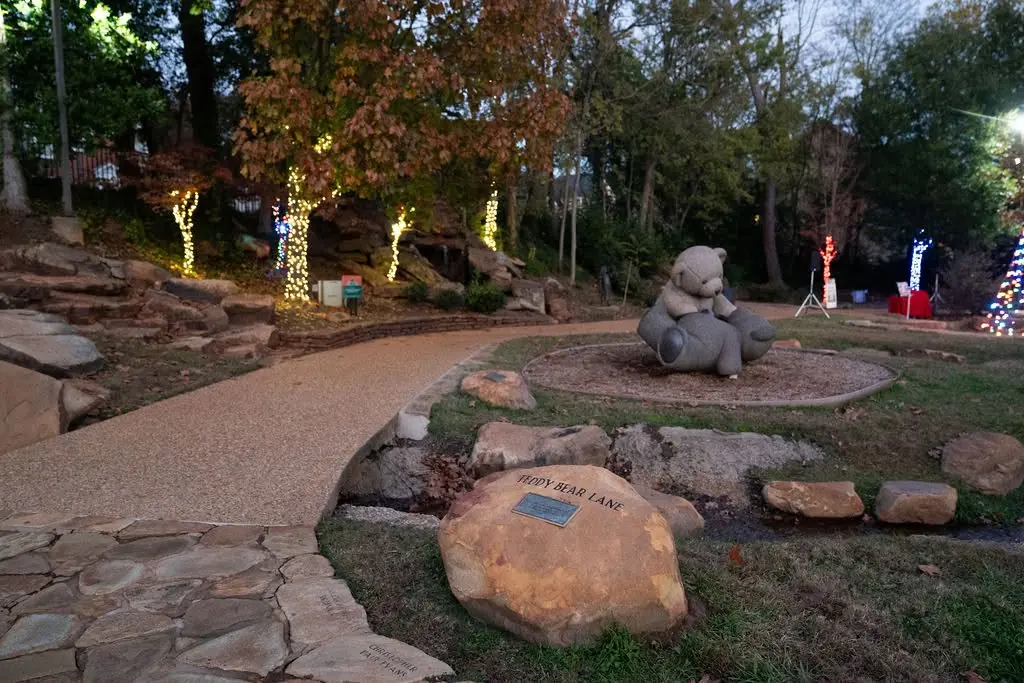 Illuminated park paths around a bear statue