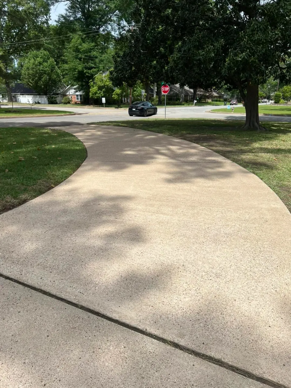 The same driveway after washing, an even tan surface curving out to the street