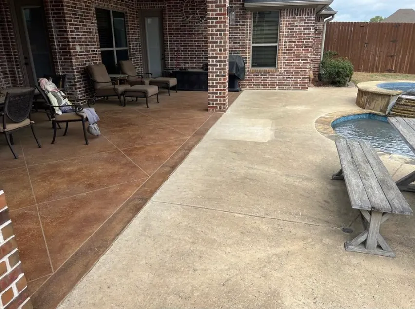 A concrete pool deck beside a brick home before washing, darkened and stained